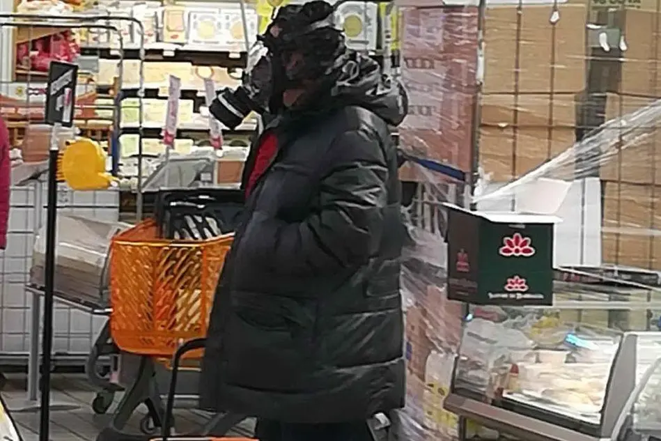 Un signore al supermercato con la maschera antigas