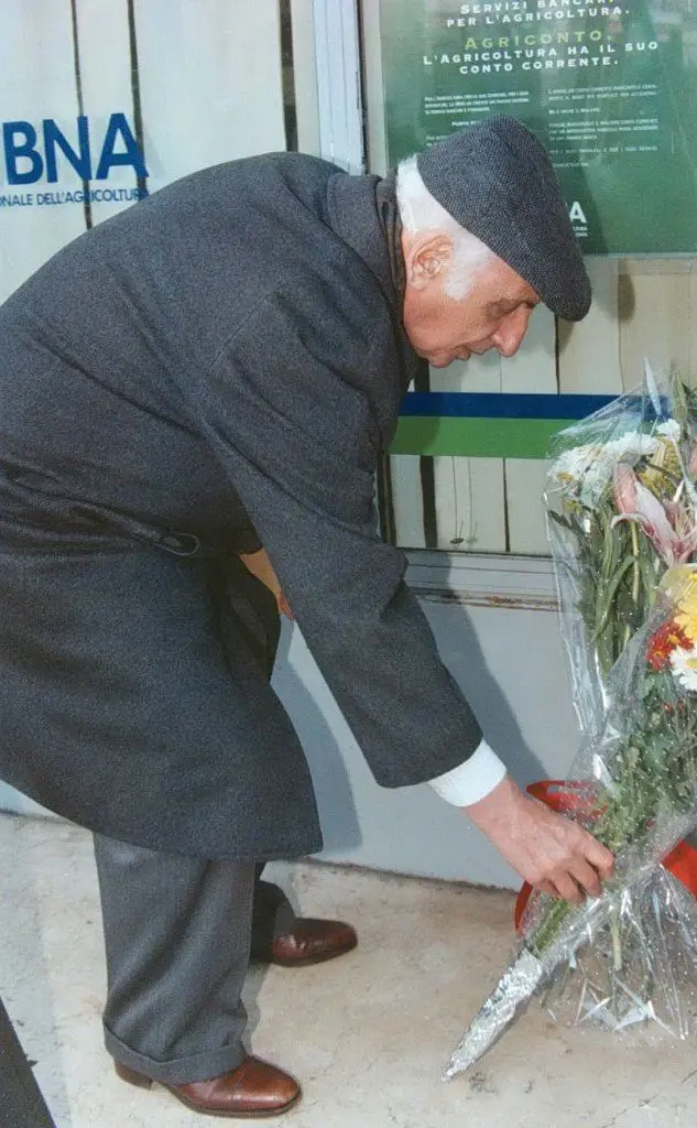 Un uomo posa dei fiori all'ingresso della banca nel giorno dell'anniversario