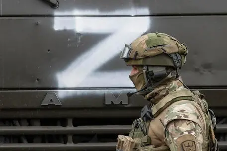 Un soldato ucraino accanto a un carro armato russo (Ansa)
