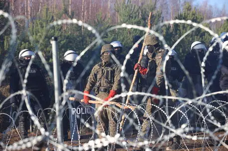 A handout picture made available by Belta news agency shows Polish servicemen guarding the border line as migrants gather at the Belarus-Polish border in the Grodno region, Belarus, 09 November 2021. According to the State Border Committee of Belarus (GPK), there are more than two thousand people near the border, including women and children, who want to obtain asylum in the European Union, 'and they do not consider the territory of the Republic of Belarus as a place of stay.' The territory is guarded by several thousand employees of the Polish special services. The migration crisis at the border of Belarus has been going on since the spring of 2021. Belarusian President Lukashenko said that after the introduction of new EU sanctions against Minsk, the Belarusian authorities will no longer interfere with the movement of illegal migrants to the European Union. ANSA/LEONID SCHEGLOV/BELTA HANDOUT HANDOUT EDITORIAL USE ONLY/NO SALES