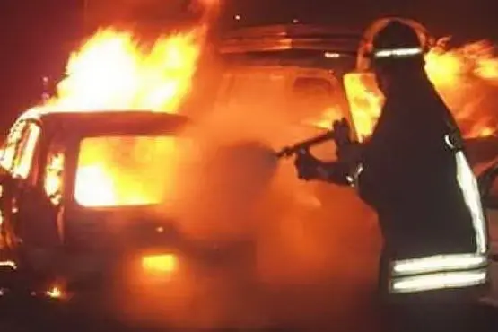 Un vigile del fuoco spegne l'incendio di un'auto