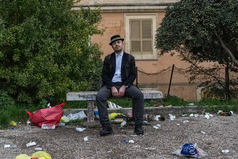 L'autore dell'articolo seduto su una panchina circondata da rifiuti (foto Twitter)