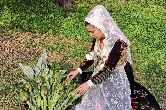 Una ragazza in costume di Uri accanto a una cesta di carciofi spinosi (Archivio)