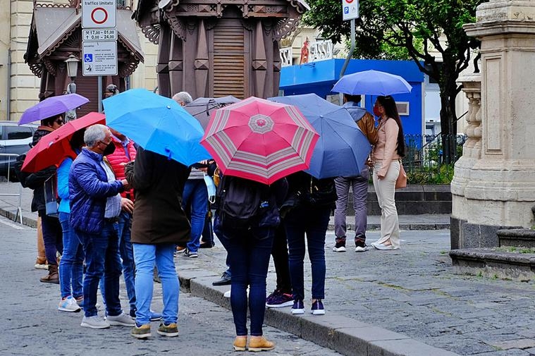 Un gruppo di turisti passeggia con gli ombrelli aperti (Ansa)
