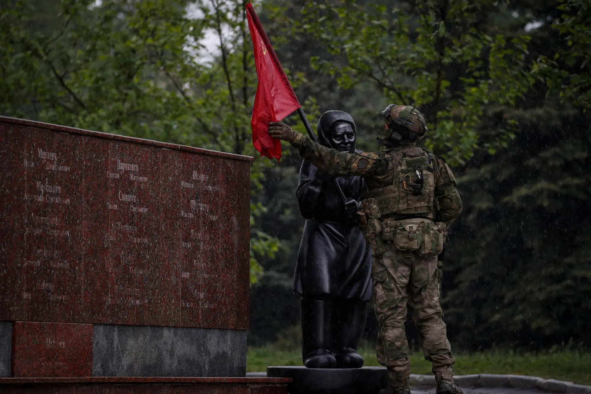 epa09956653 A picture taken during a visit to Mariupol organized by the Russian military shows a Russian serviceman adjusting the Soviet flag on a statue of a grandmother in Leninsky Komsomol Square in downtown of Mariupol, Ukraine, 18 May 2022. The statue was erected in early May and it relates to a video that started circulating in April showing an elderly woman in a village on the outskirts of Kharkiv waving the Soviet flag to Ukrainian troops, mistaken them for Russian soldiers. On 24 February, Russian troops invaded Ukrainian territory starting a conflict that has provoked destruction and a humanitarian crisis. According to the UNHCR, more than six million refugees have fled Ukraine, and a further 7.7 million people have been displaced internally within Ukraine since. EPA/SERGEI ILNITSKY