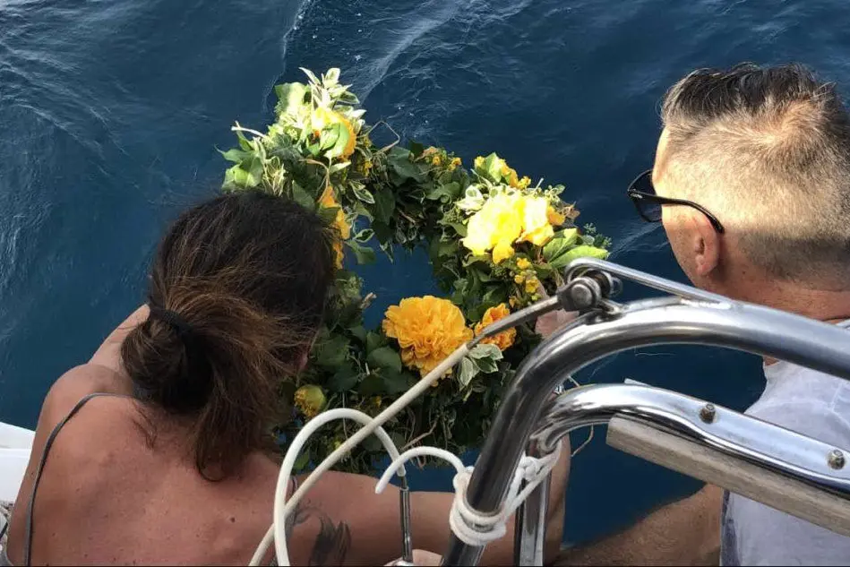 La madre di Massimiliano getta in mare una corona di fiori dopo aver sparso le ceneri di suo figlio (foto L'Unione Sarda - Murgana)