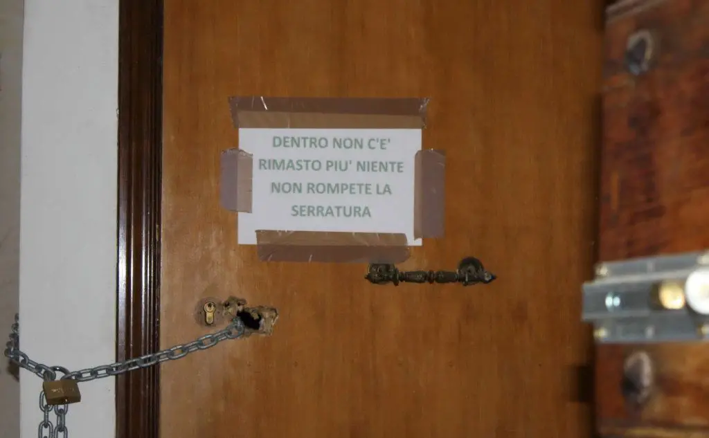 Il cartello contro gli sciacalli sulla porta di un casa abbandonata a Fossa (L'Aquila)