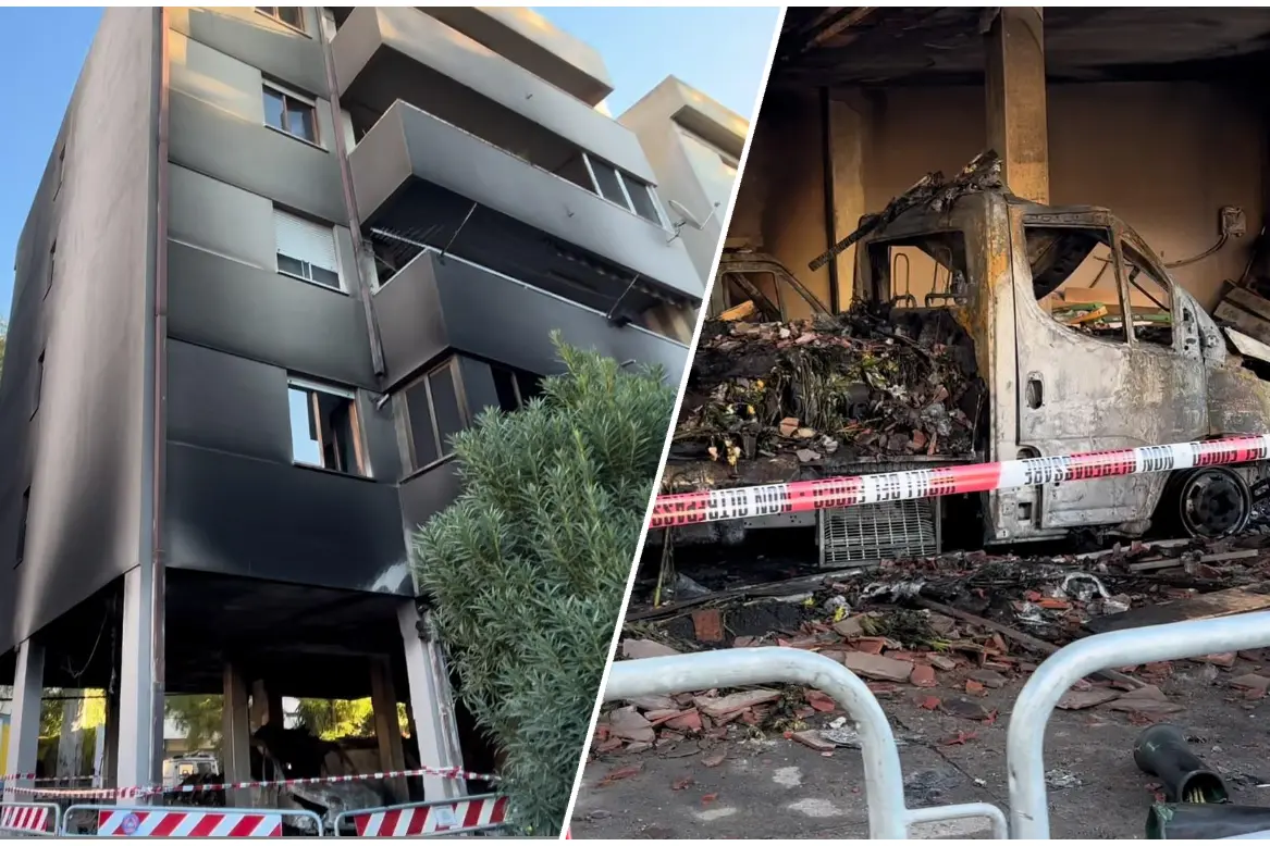 La palazzina e uno dei due furgoni dopo il rogo (foto Carta)