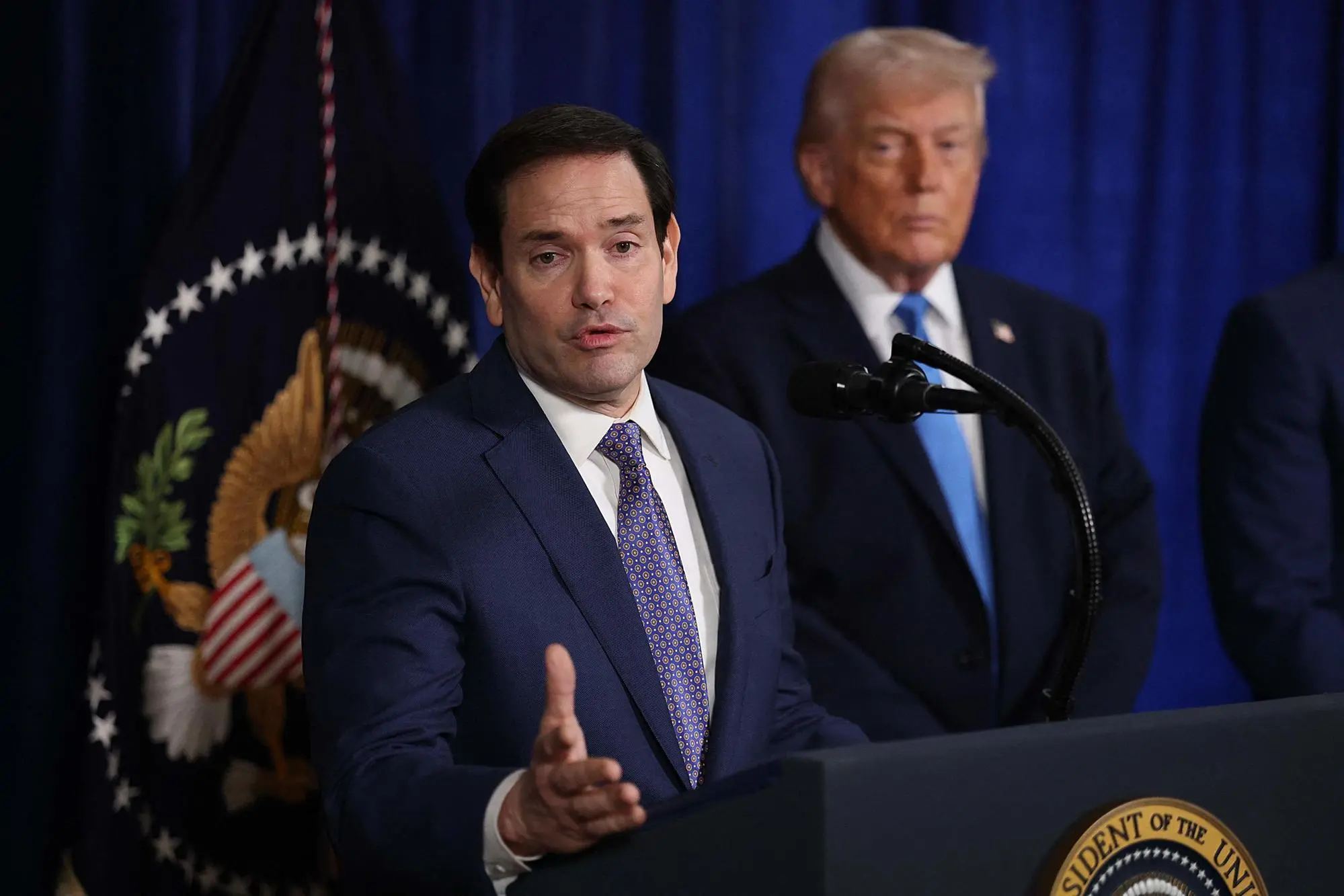 PALM BEACH, FLORIDA - JANUARY 03: U.S. Secretary of State Marco Rubio speaks during a press conference as U.S. President Donald Trump listens at Mar-a-Lago club on January 03, 2026, in Palm Beach, Florida. During the event, President Trump confirmed that the U.S. military carried out a large-scale strike in Caracas overnight, resulting in the capture of Venezuelan leader Nicolas Maduro and his wife, Cilia Flores. Joe Raedle/Getty Images/AFP (Photo by JOE RAEDLE / GETTY IMAGES NORTH AMERICA / Getty Images via AFP)
