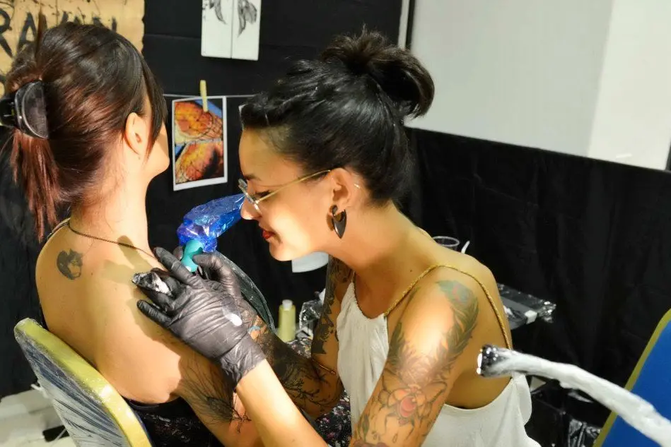 Una tatuatrice al lavoro durante la convention del 2015 a Quartu