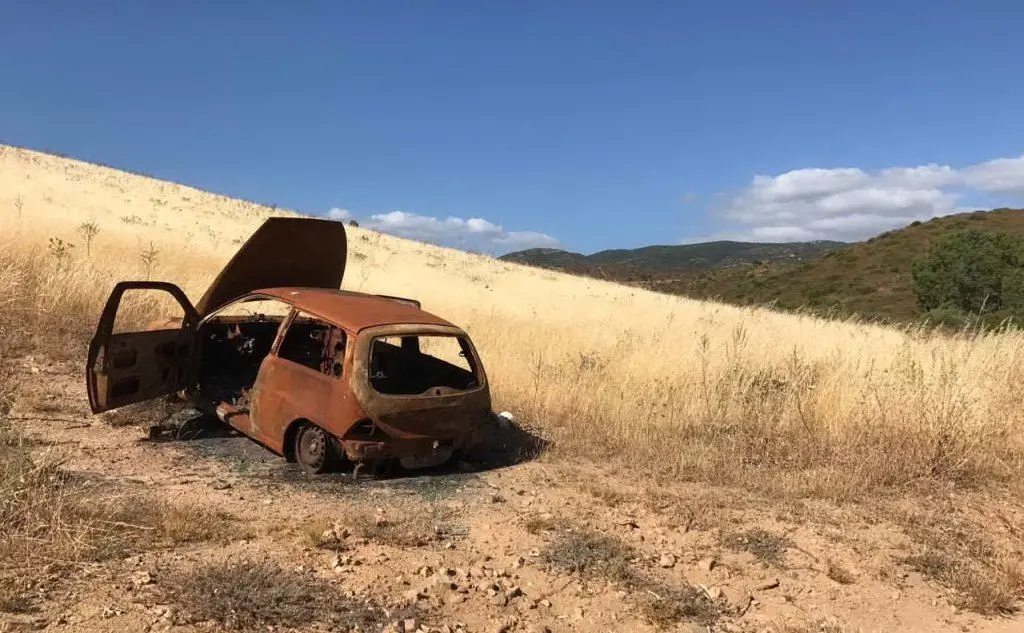 La carcassa di un'auto abbandonata in campagna