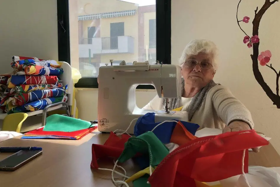Una delle anziane di Pula al lavoro per confezionare bandierine
