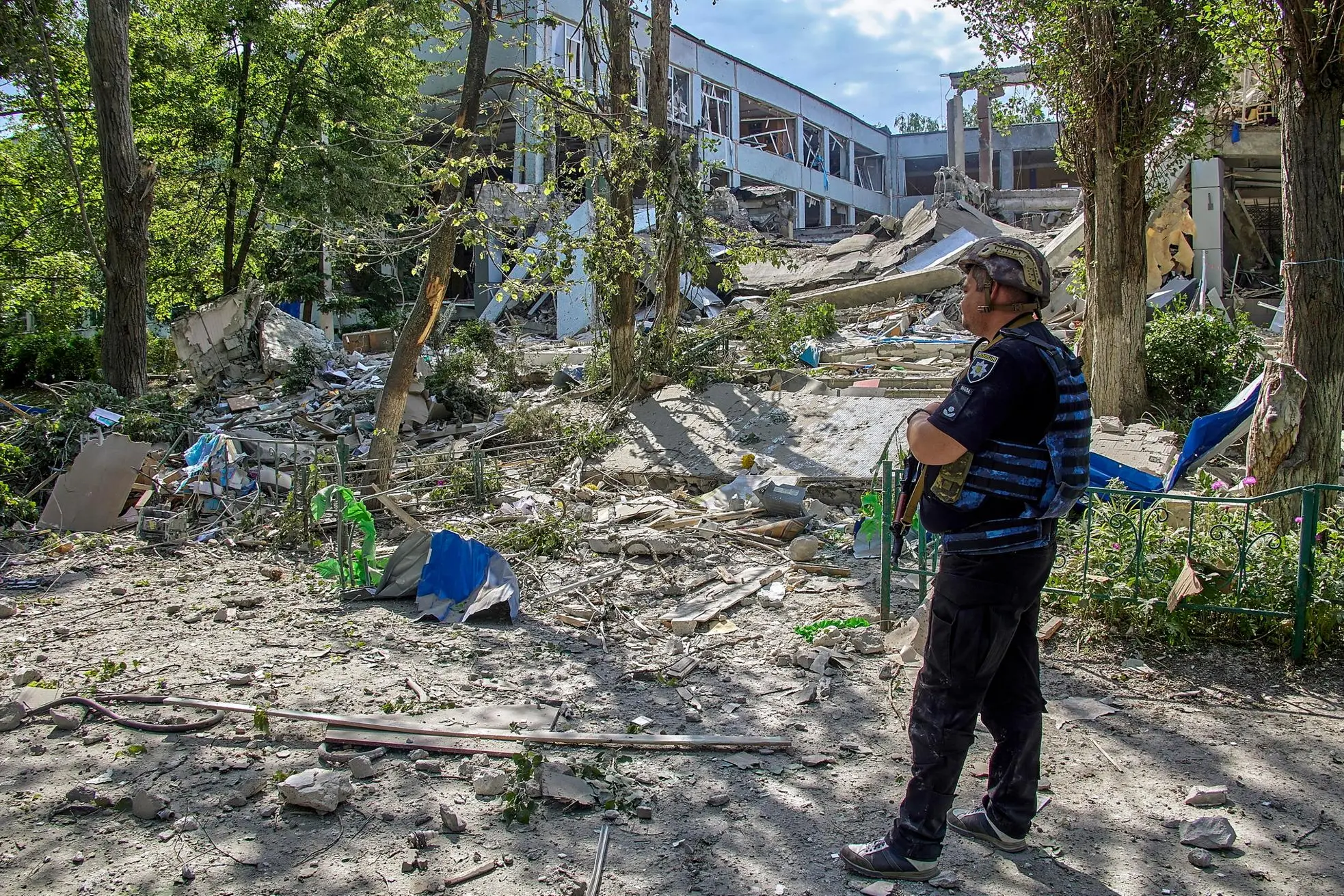 epa09991515 A policeman stands near a damaged school in the aftermath of an overnight rocket attack near Kharkiv, Ukraine, 02 June 2022. Russian troops on 24 February entered Ukrainian territory, starting a conflict that has provoked destruction and a humanitarian crisis. According to data released by the United Nations refugee agency UNHCR on 29 May, over 6.8 million people have fled Ukraine since Russian troops entered the country on 24 February 2022. EPA/SERGEY KOZLOV