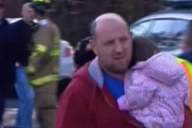 Un uomo con un bambino in braccio esce dalla scuola del terrore