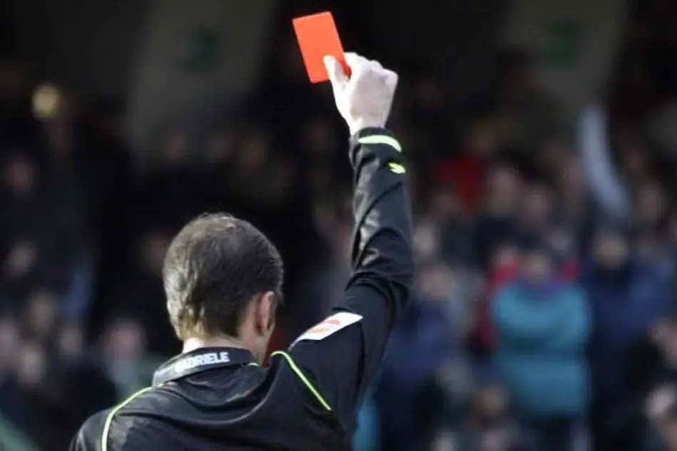 Un arbitro col cartellino rosso (foto L'Unione Sarda)