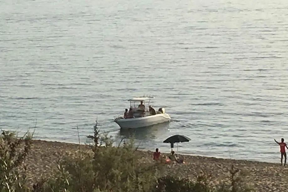 I bagnini impegnati ad allontanare l'imbarcazione dalla spiaggia