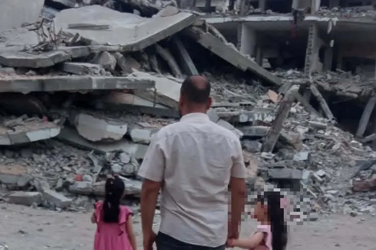 Mohammed e le figlie davanti alle macerie di Gaza