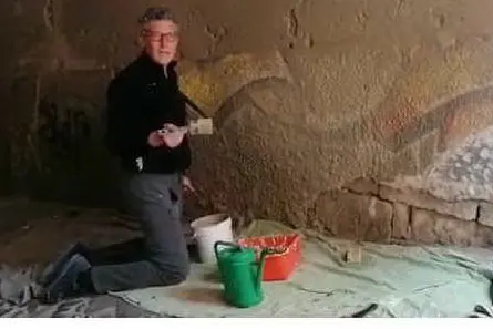 Andrea Formaini ripulisce un muro di Castello a Cagliari (foto C. Ra.)
