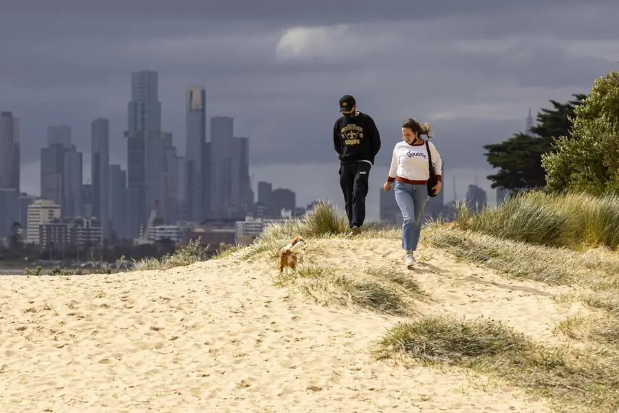 Due persone a passeggio su una spiaggia di Melbourne (Ansa)