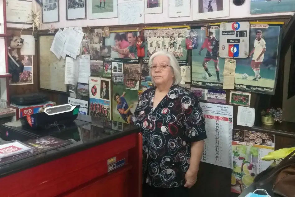Pietrina Marras, 76 anni, davanti a una delle pareti disseminate di foto e ricordi legati al Cagliari (foto L'Unione Sarda)