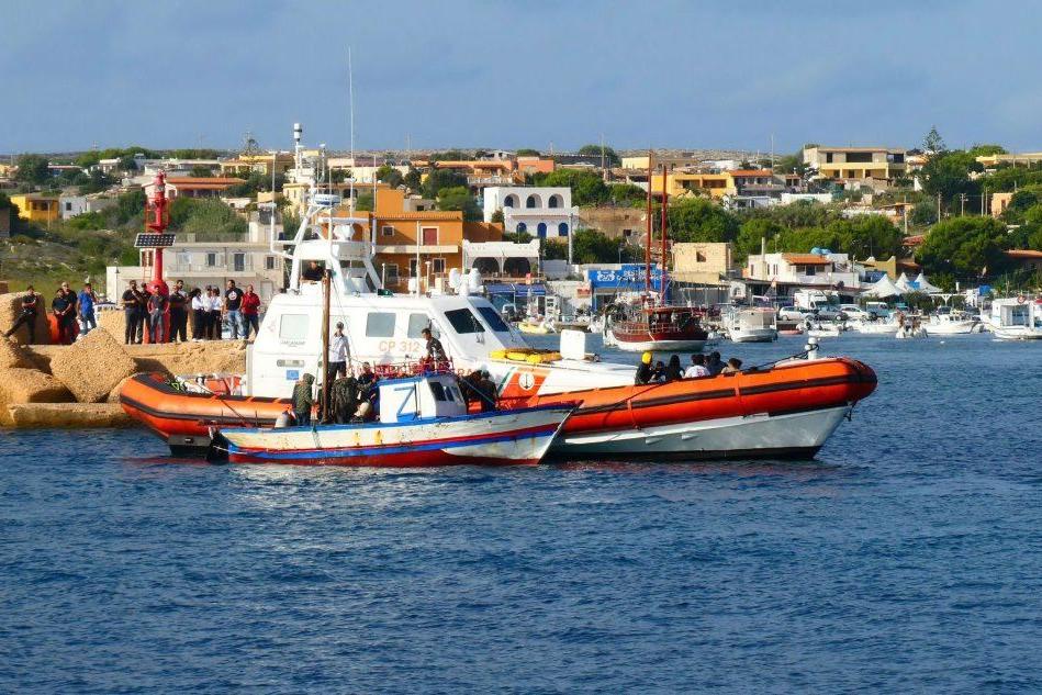 La Guardia costiera di Lampedusa accanto a un barchino di migranti (Ansa)