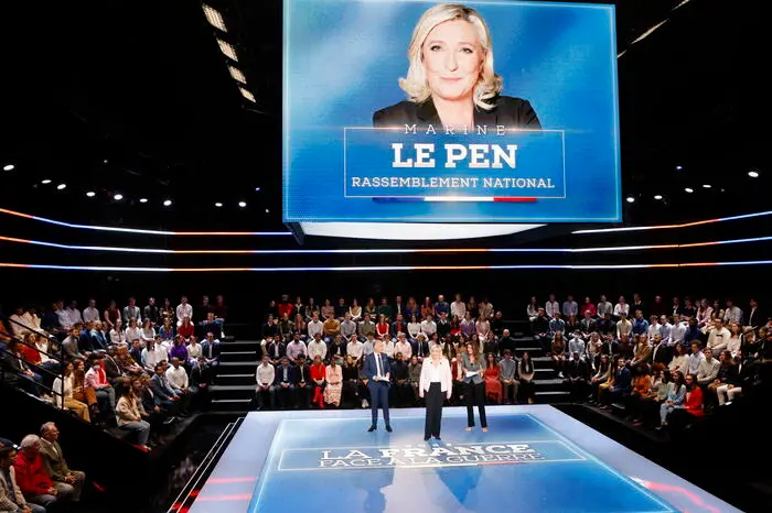 epa09825119 French far-right Rassemblement National (RN) party Member of Parliament and presidential candidate Marine Le Pen (C) stands next to French journalists and TV hosts Anne-Claire Coudray (R) and Gilles Bouleau (L) during the show 'La France face a la guerre' (France in the Face of War), broadcasted on French TV channel TF1, in Saint-Denis, north of Paris, 14 March 2022. The special broadcast gathers eight of the twelve candidates for France's April 2022 presidential election to speak on the war in Ukraine, following Russia's military invasion. EPA/LUDOVIC MARIN / POOL