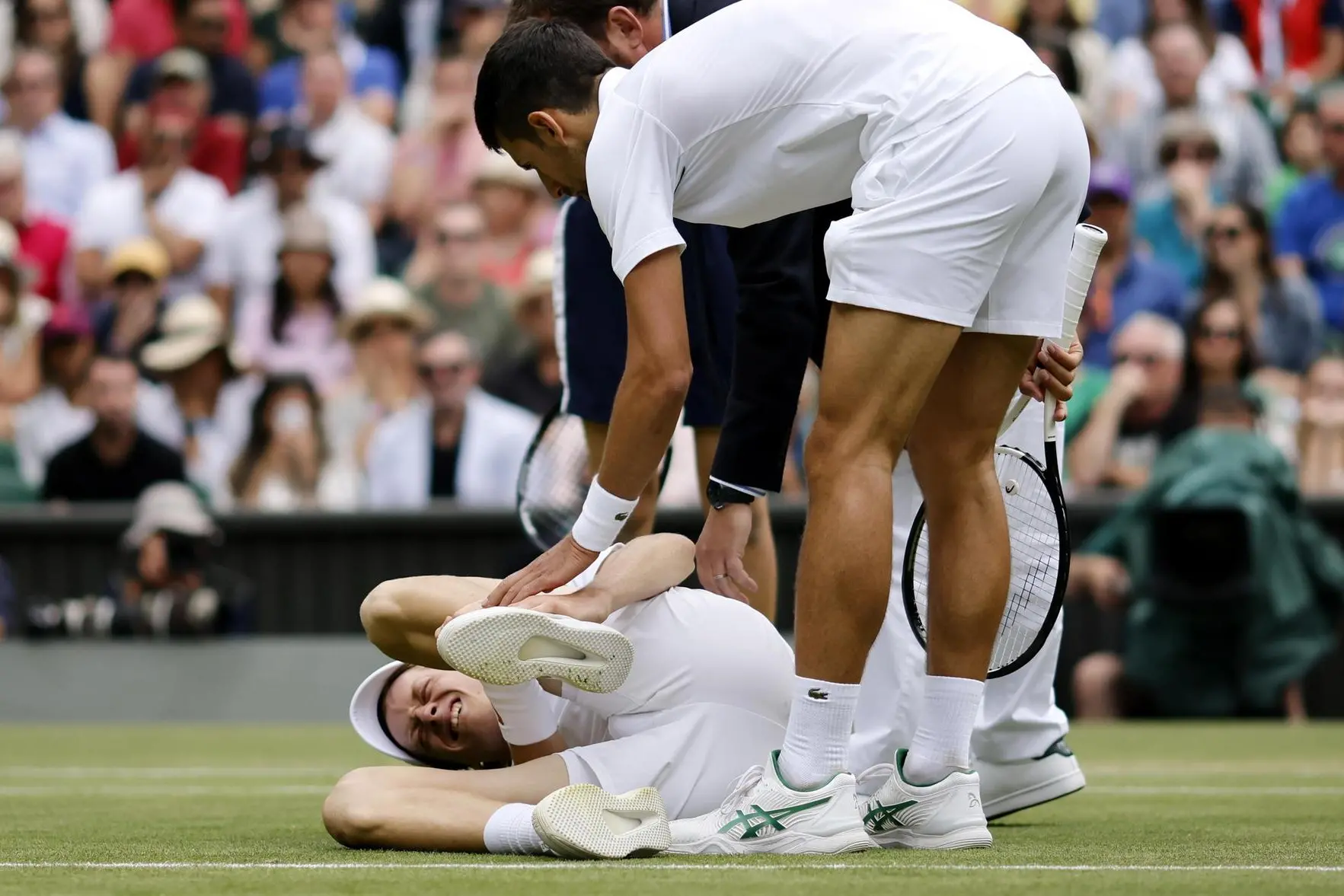 epa10053590 Jannik Sinner (L) of Italy is helped by his opponent Novak Djokovic of Serbia after falling on court in their men's quarter final match at the Wimbledon Championships, in Wimbledon, Britain, 05 July 2022. EPA/TOLGA AKMEN EDITORIAL USE ONLY