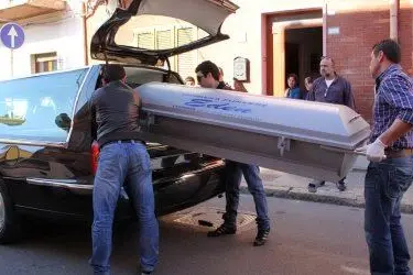 La bara col corpicino del bambino viene portata via dalla casa del delitto - foto Mundula