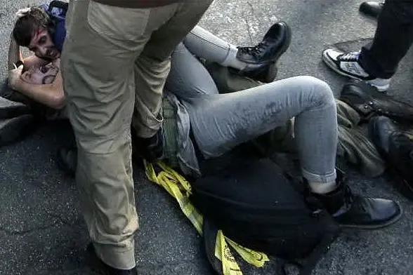 Il momento in cui l'agente calpesta la manifestante a terra