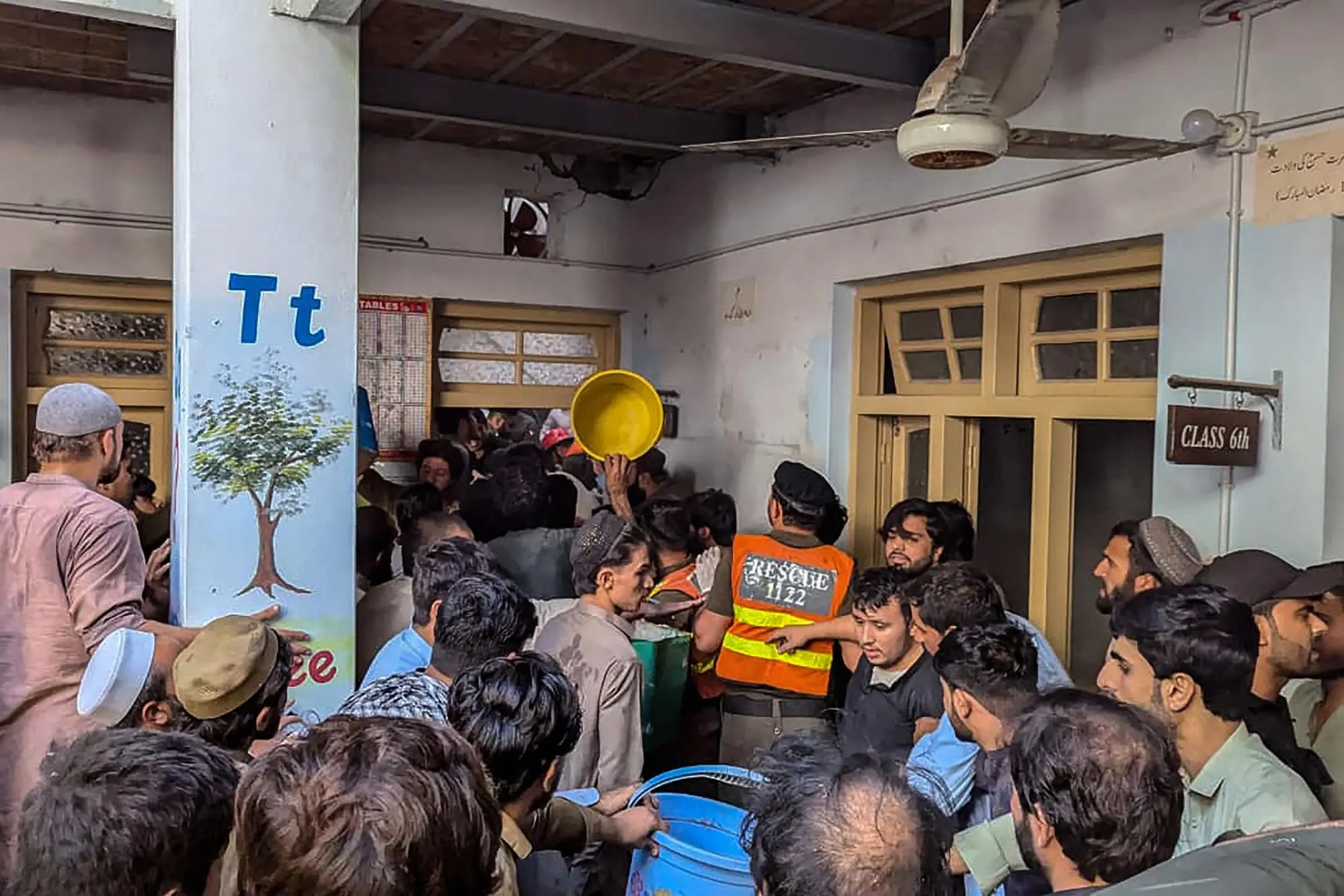This photograph taken and released by the Khyber Pakhtunkhwa province's Emergency Service (Rescue 1122) on October 15, 2026 shows rescue workers and residents during a search operation after a roof collapsed at a school in Peshawar. Sixteen pupils and a teacher were killed on October 15 after a roof collapsed at a school in the northwest Pakistani city of Peshawar, emergency services said. (Photo by Handout / Khyber Pakhtunkhwa province's Emergency Service (Rescue 1122) / AFP) / RESTRICTED TO EDITORIAL USE - MANDATORY CREDIT "AFP PHOTO /Khyber Pakhtunkhwa province's Emergency Service (Rescue 1122)/ HANDOUT / " - NO MARKETING NO ADVERTISING CAMPAIGNS - DISTRIBUTED AS A SERVICE TO CLIENTS