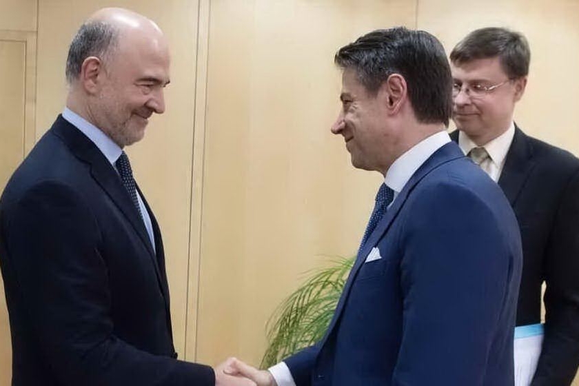 Stretta di mano tra il commissario Ue Moscovici e il premier Conte sotto gli occhi di Valdis Dombrovskis (Archivio L'Unione Sarda)