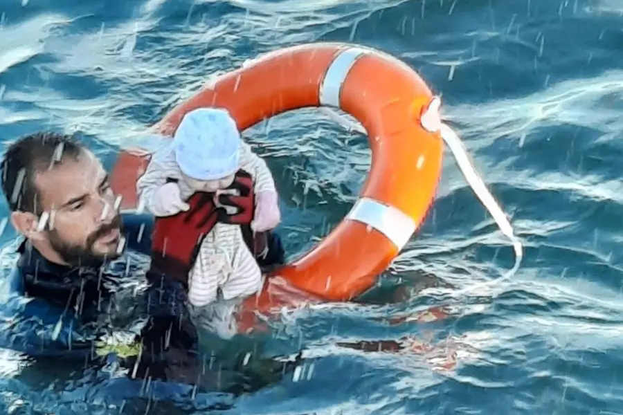 Un neonato viene soccorso a Ceuta, in una foto twittata dalla Guardia Civil (via Ansa)