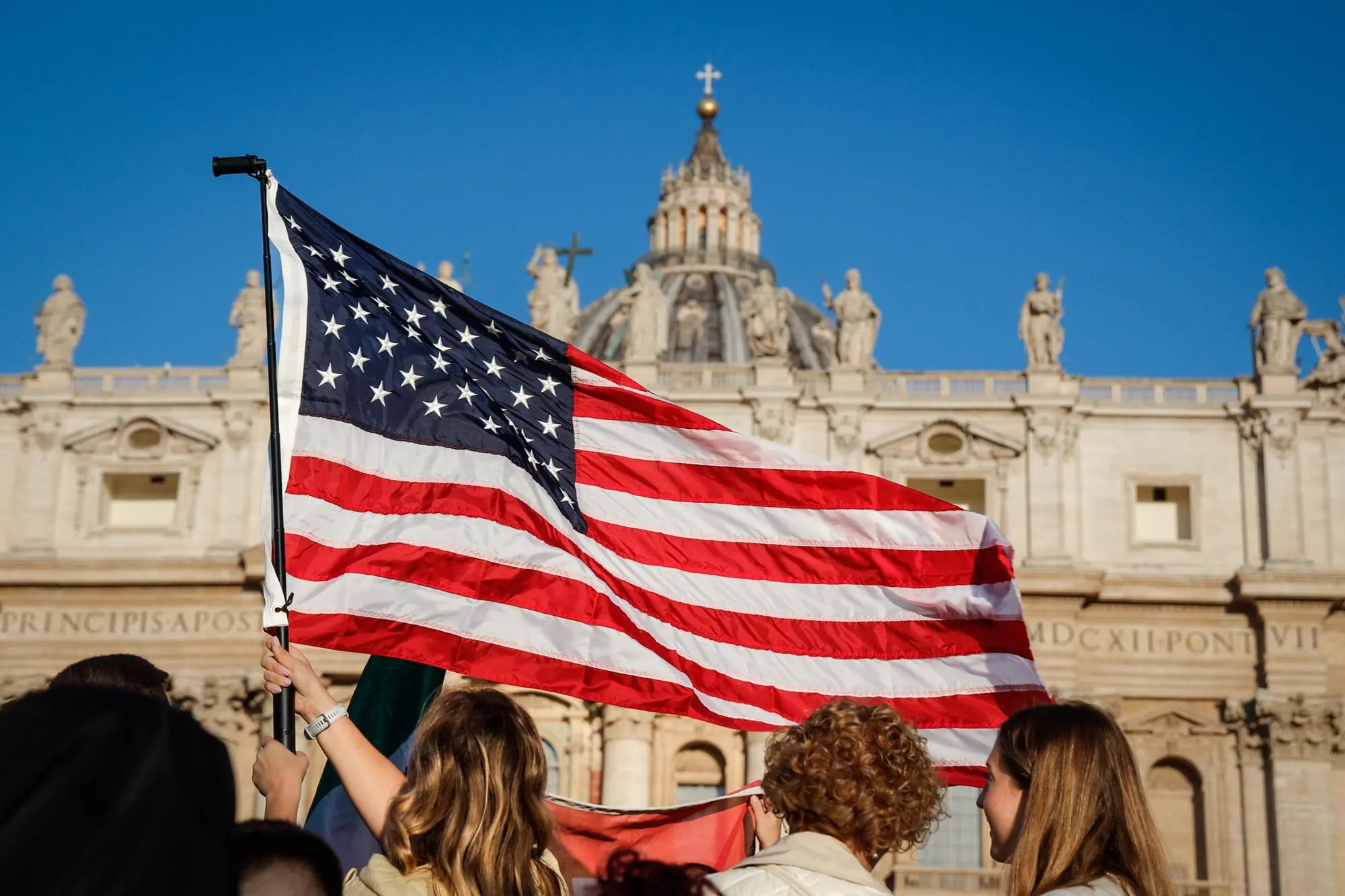 A United States flag flies in front of the dome in St. Peter's Square, Vatican City, May 18, 2025. ANSA/GIUSEPPE LAMI (bandiera, stati uniti, san pietro)