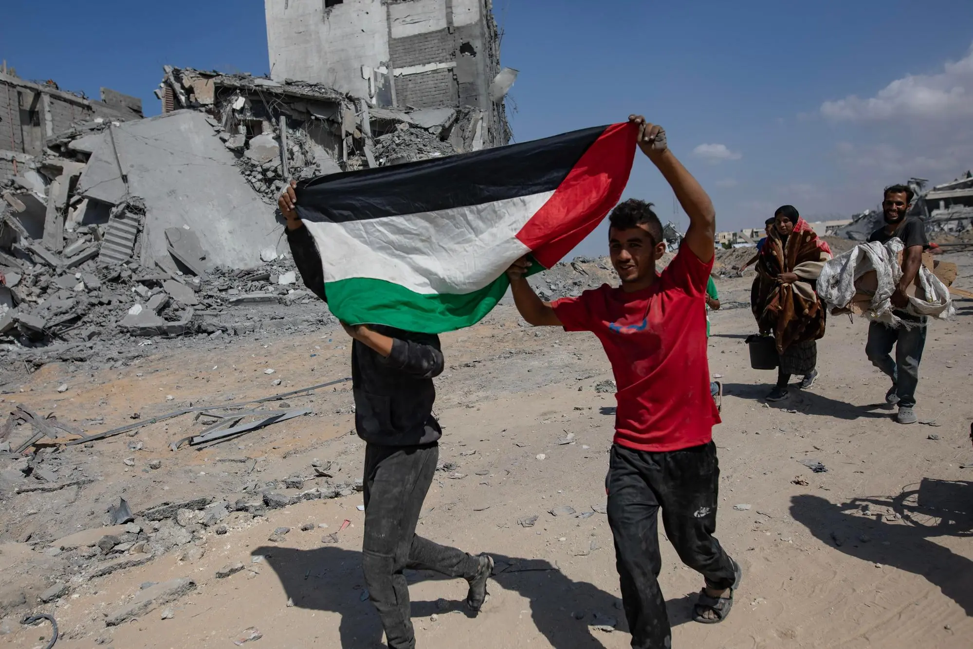 epaselect epa12445969 Two people hold the Palestinian flag as they return to inspect their homes after the Israeli army withdrew from some areas east of Khan Yunis in the southern Gaza Strip, 10 October 2025. Israeli Prime Minister Benjamin Netanyahu's office announced on 09 October that the Israeli government had approved the Gaza ceasefire and hostage release plan. EPA/HAITHAM IMAD