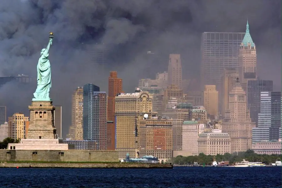 La Statua della Libertà e sullo sfondo i grattacieli di Manhattan avvolti da una densa coltre di fumo dopo l'attentato (Ansa)