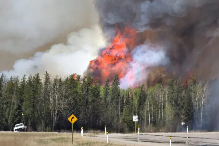 Flames a smoke rise from a wildfire in Fort McMurray, Alberta, Friday, May 6, 2016. More than 80,000 people have left Fort McMurray in the heart of Canada oil sands, where the fire has torched over 1,000 homes and other buildings. (Jason Franson /The Canadian Press via AP) MANDATORY CREDIT