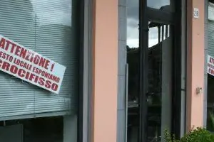 I cartelli alle vetrine dei negozi di Carbonia