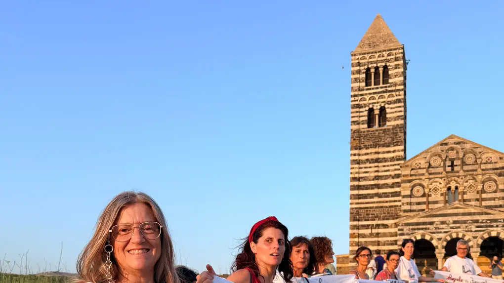 Gruppo di persone abbraccia la basilica di Saccargia in un gesto simbolico per difendere il paesaggio e l’identità sarda