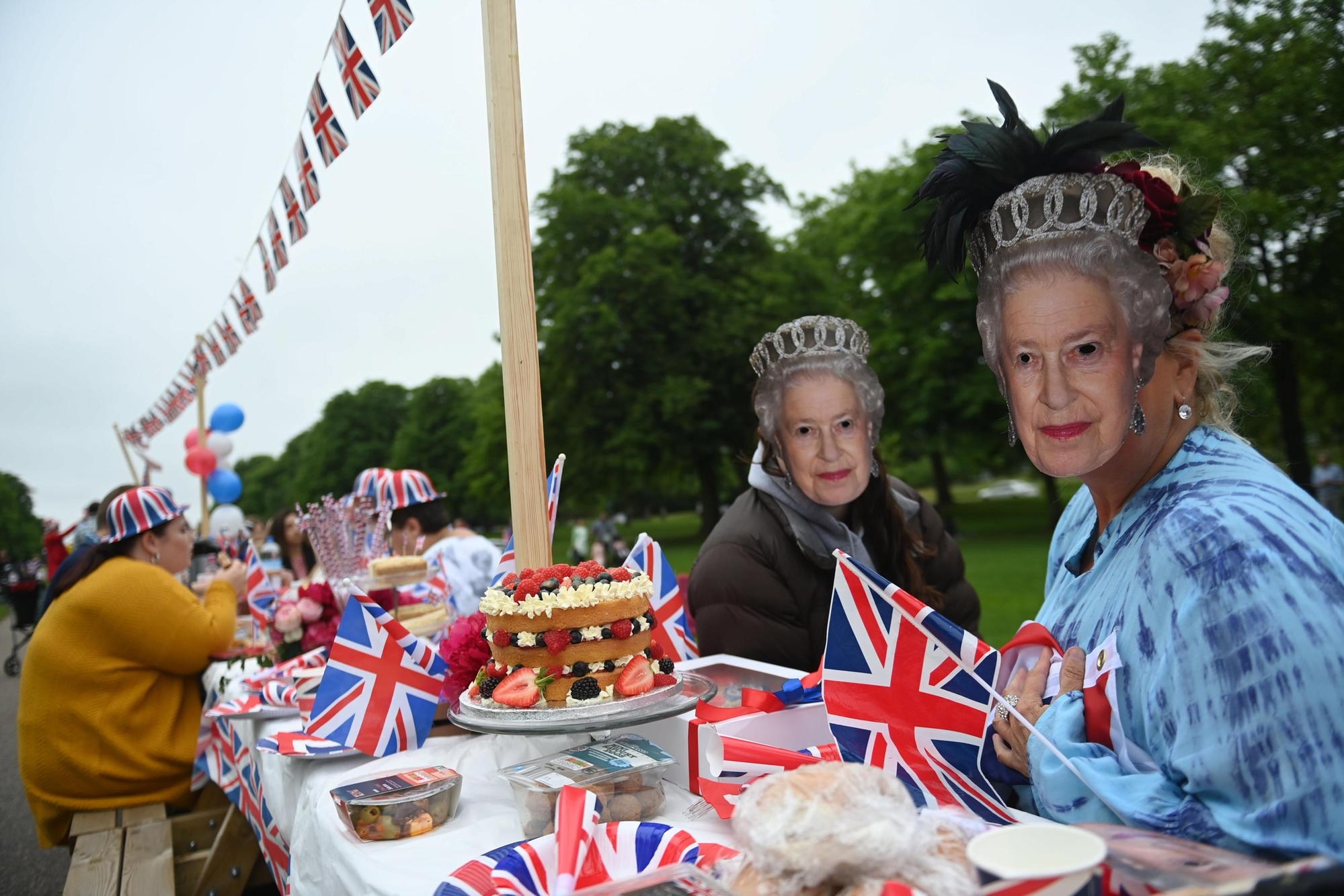 epa09997581 People in Queen masks enjoy a picnic as they take part in The Big Lunch on the Long Walk, during the celebrations of thePlatinum Jubilee of Queen Elizabeth II, in Windsor, Britain, 05 June 2022. Britain is enjoying a four day holiday weekend to celebrate the Platinum Jubilee of Britain's Queen Elizabeth II marking the 70th anniversary of her accession to the throne on 06 February 1952. EPA/NEIL HALL