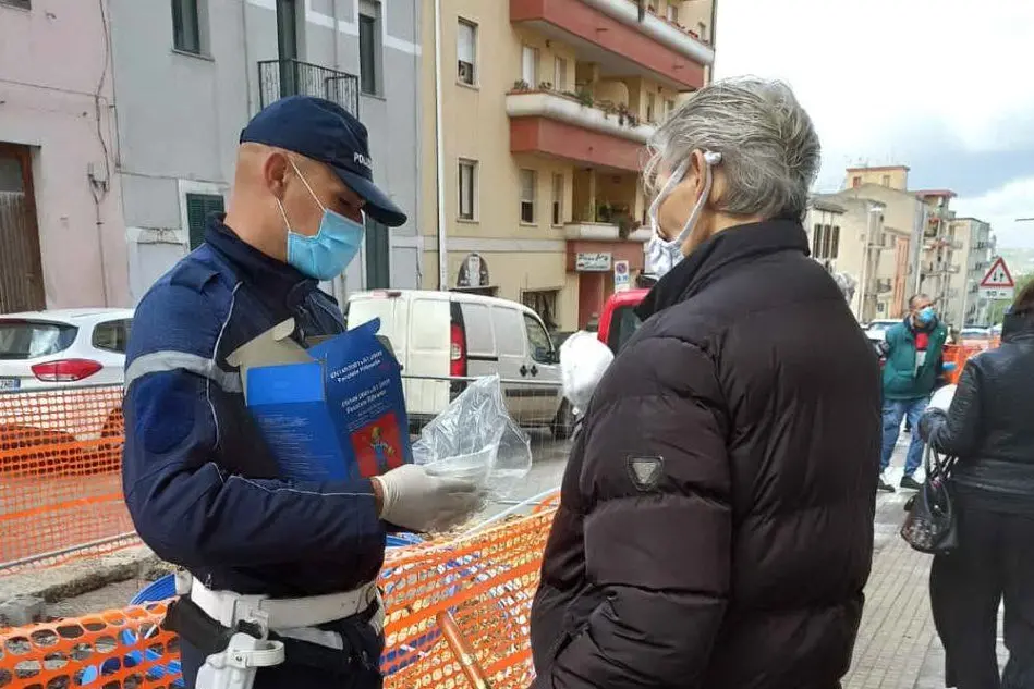 Un agente distribuisce mascherine (Foto Polizia locale Sassari)