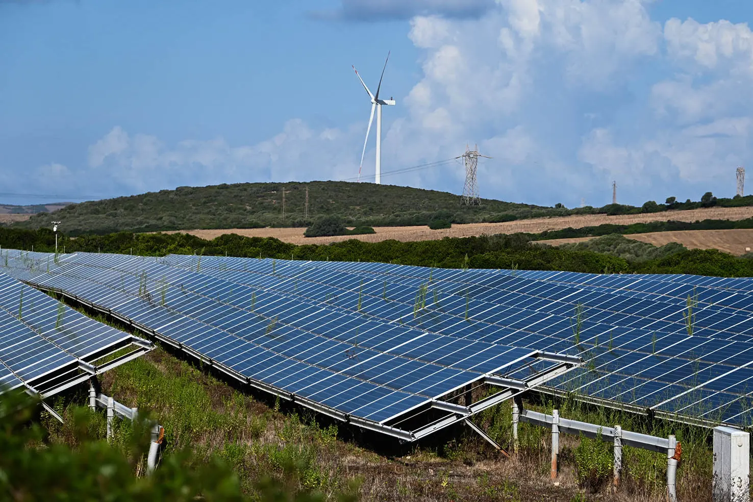 Un impianto fotovoltaico, sullo sfondo pale eoliche (L'Unione Sarda)