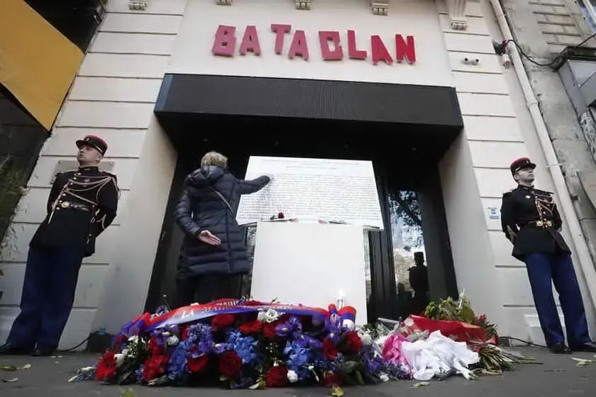 Una donna tocca la targa commemorativa all'ingresso del Bataclan (Archivio L'Unione Sarda)