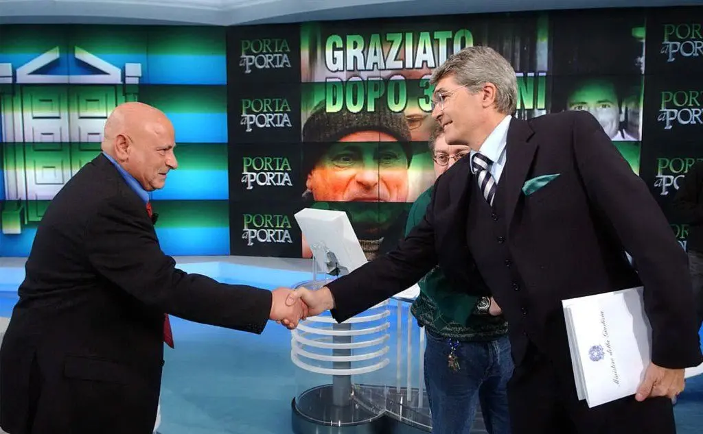 Stringe la mano all'ora ministro della Giustizia Roberto Castelli durante la trasmissione &quot;Porta a porta&quot; (Ansa)