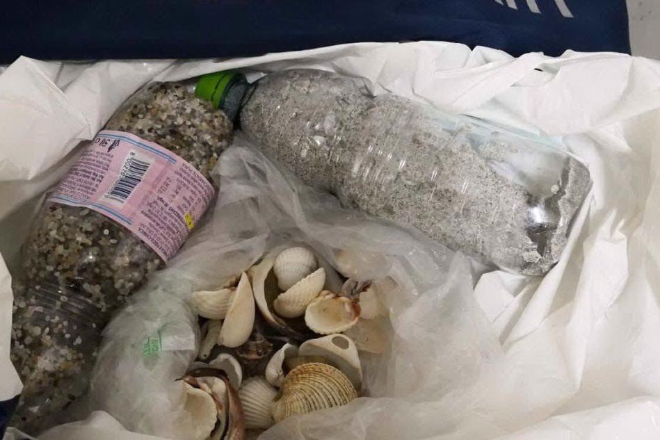Le bottiglie e il sacco sequestrati (Foto Autorità di Sistema Portuale del Mare di Sardegna)