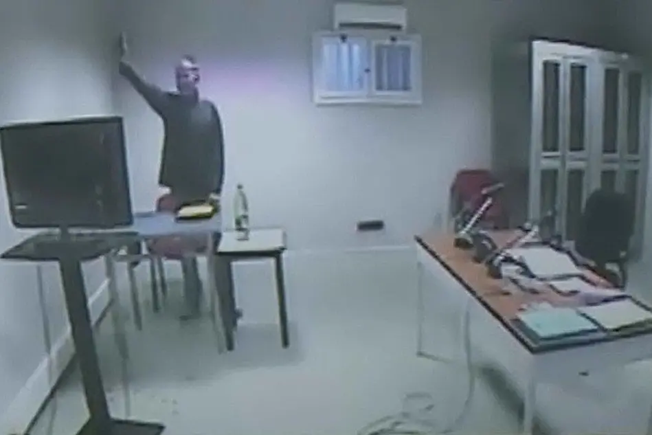 Un frame da un video di Rai News 24 che mostra Massimo Carminati, in collegamento da Parma, che fa il saluto romano rivolto alla telecamera durante l'interrogatorio del 2017 (Ansa/Rai News 24)