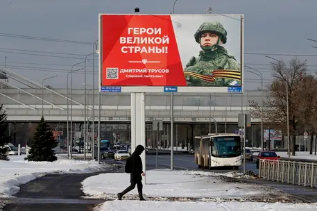 epa10493913 People cross a street bus under a billboard depicting a soldier with the slogan 'Glory to the Heroes of Russia' in St. Petersburg, Russia, 27 February 2023. On 24 February 2022 Russian troops entered the Ukrainian territory in what the Russian president declared to be a 'Special Military Operation', starting an armed conflict that has provoked destruction and a humanitarian crisis. EPA/ANATOLY MALTSEV