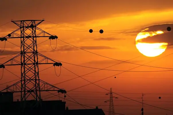 Tramonto sui tetti con tralicci e cavi elettrici