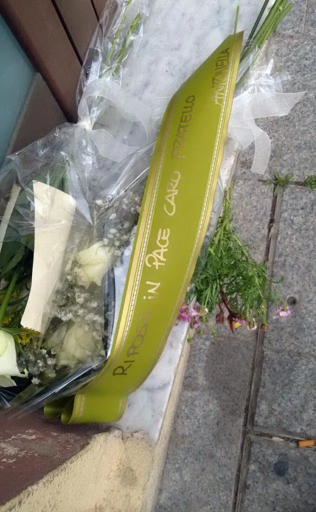 Il messaggio con i fiori sul portone della palazzina che ospita il centro migranti