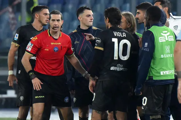 L'arbitro Giovanni Ayroldi accerchiato dai giocatori del Cagliari e da Davide Nicola (foto Ansa)