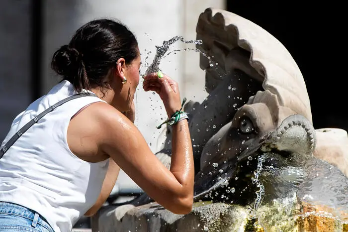 Una turista si rinfresca per il caldo nella fontana di piazza Colonna, Roma, 30 agosto 2024. ANSA/ANGELO CARCONI